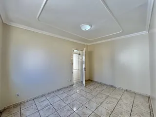Interior de uma sala com piso de cerâmica clara e paredes brancas.