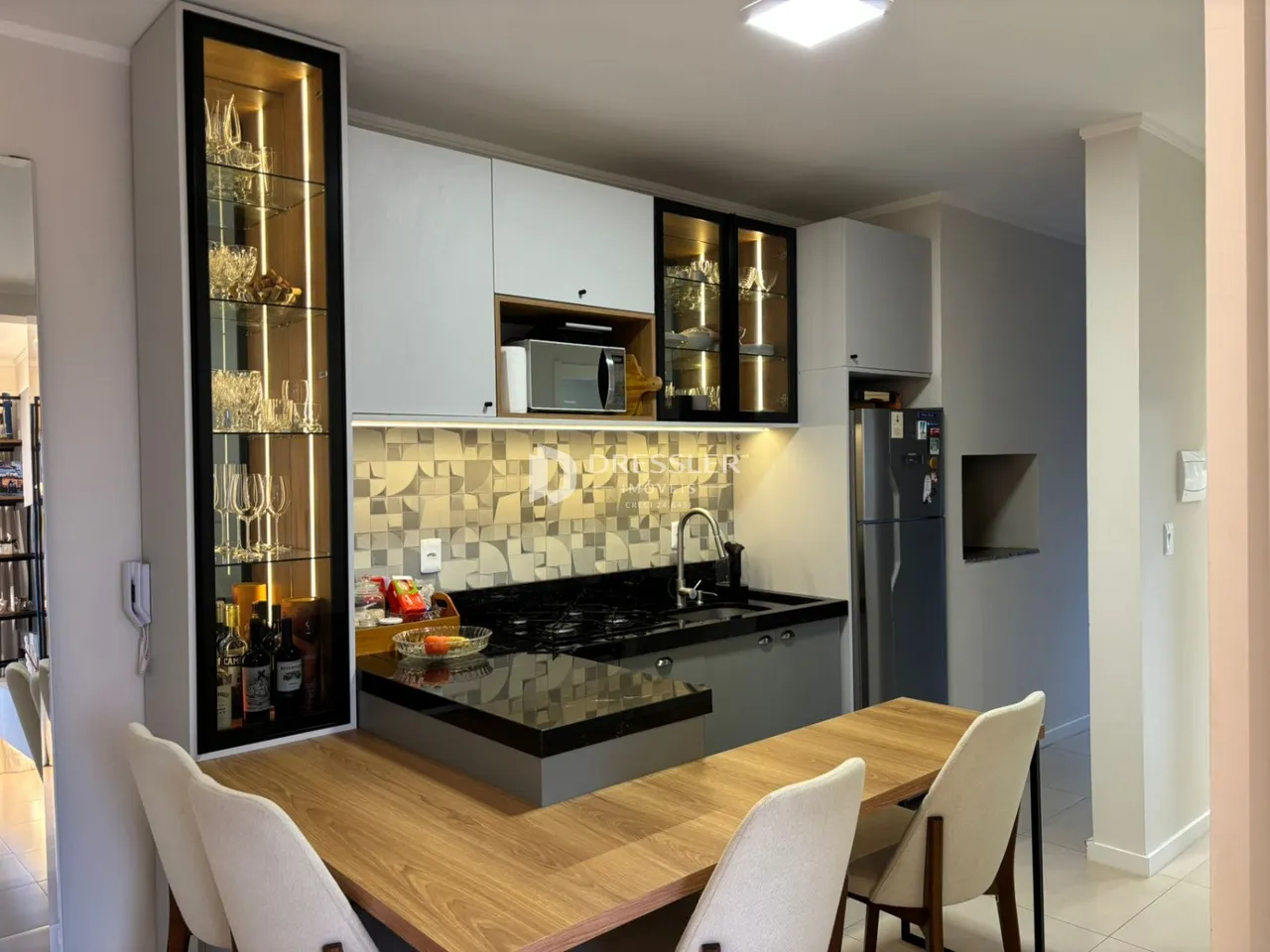 Cozinha moderna com armários brancos e bancada escura em Lajeado.
