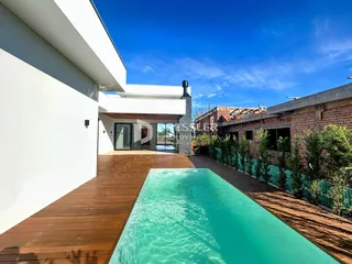 Fachada de uma residência com piscina e deck de madeira.