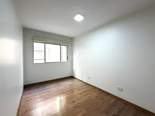 Uma sala com piso de madeira clara e janela.