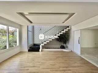 Sala de estar com piso de madeira clara e escadaria moderna em um apartamento em Lajeado.