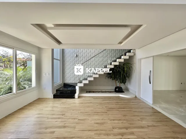Sala de estar com piso de madeira clara e escadaria moderna em um apartamento em Lajeado.