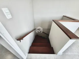 Vista de um corredor com escadaria em uma residência.