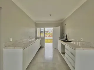 Vista de uma cozinha com armários brancos e bancadas claras.