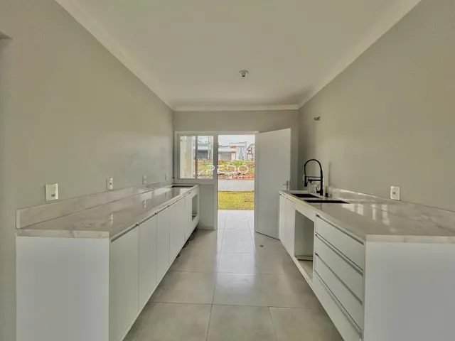 Vista de uma cozinha com armários brancos e bancadas claras.