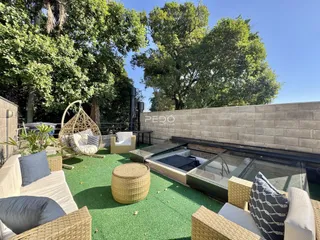 Área externa com mobiliário de jardim e piso de grama artificial.