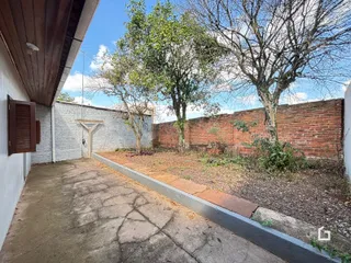 Vista lateral da propriedade com muro de tijolos vermelhos e vegetação.