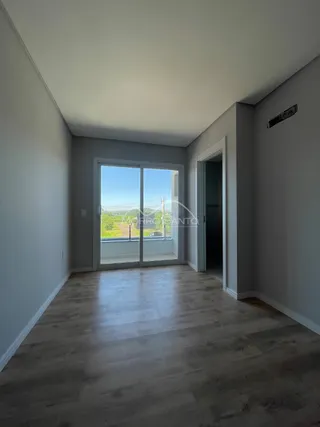 Ambiente interno com piso de madeira clara e porta de vidro que dá para a paisagem.