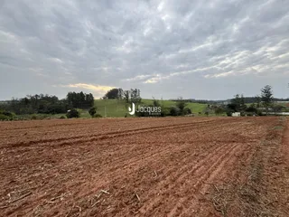 Campo aberto com colinas verdes ao fundo sob um céu nublado.