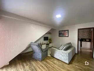 Sala de estar com piso de madeira e sofá no interior de uma residência.