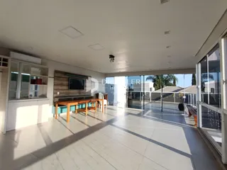Sala de estar com piso claro e portas de vidro que dão acesso ao exterior.