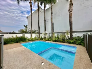 Vista externa de uma piscina e jardim em uma residência.