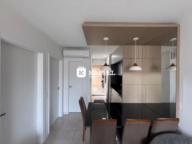 Foto de uma sala de jantar com mesa de vidro e área de cozinha moderna.