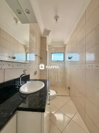 Banheiro com revestimento de azulejos brancos e bancada escura.