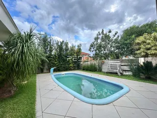 Foto de uma piscina externa em um quintal com gramado e vegetação.