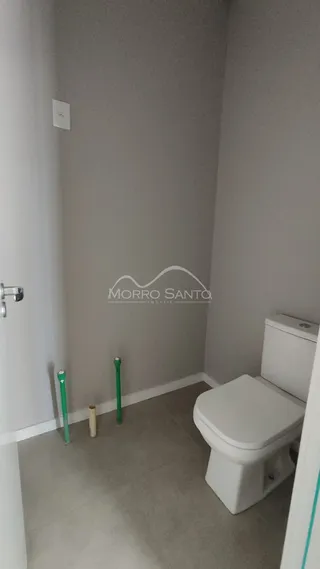 Foto de um corredor interno com paredes brancas e um vaso sanitário branco.