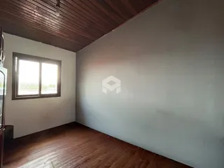Vista interna de um cômodo com piso de madeira e teto de madeira.