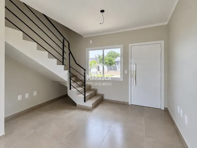 Hall com escadas e piso de cerâmica claro em uma residência.