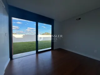 A sala de estar possui piso de madeira e uma grande porta de vidro com vista para o jardim.
