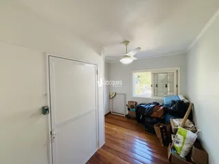 Hall de entrada com piso de madeira e porta branca.