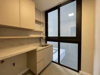 Cozinha com armários brancos e bancada clara.
