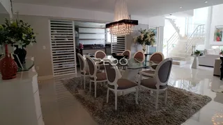 Sala de jantar com mesa de vidro e cadeiras brancas em um ambiente moderno.
