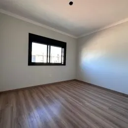 Vista interna de um cômodo com piso de madeira e janela.