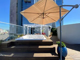 Uma área de lazer externa com jacuzzi e deck de madeira em uma residência.