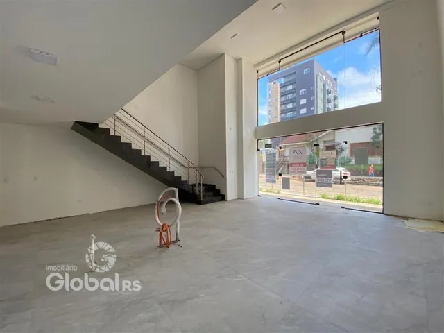 Interior de um espaço amplo com escadaria e grande janela.