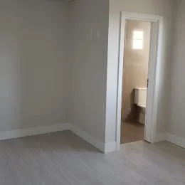 Vista interna de um corredor com paredes brancas e piso claro.