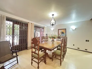 Uma sala de jantar com mesa de madeira e cadeiras em um imóvel no Brasil.