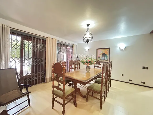 Uma sala de jantar com mesa de madeira e cadeiras em um imóvel no Brasil.