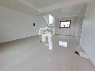 Espaço interno amplo com piso claro e escadaria visível.