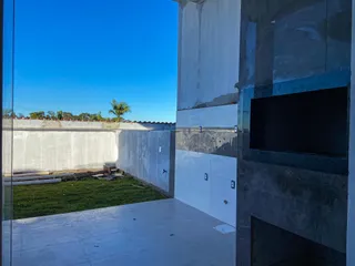 Vista externa de uma área com piso de concreto e gramado em uma construção.