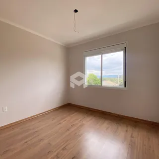 Ambiente interno de uma sala com piso de madeira e janela.