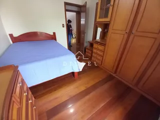 Quarto com cama de madeira e armário de madeira no interior da residência.