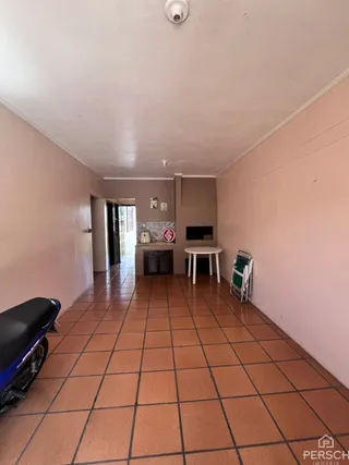 Foto de um corredor interno com piso de ladrilhos marrons.