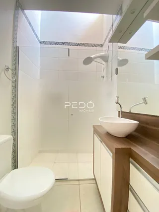 Foto interna de um banheiro com revestimento branco e bancada de madeira.