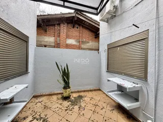 Vista de um pátio interno com piso de cerâmica e paredes brancas.