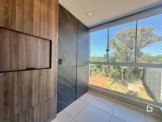 Interior de um ambiente com revestimento de madeira e piso claro, com vista para a natureza.