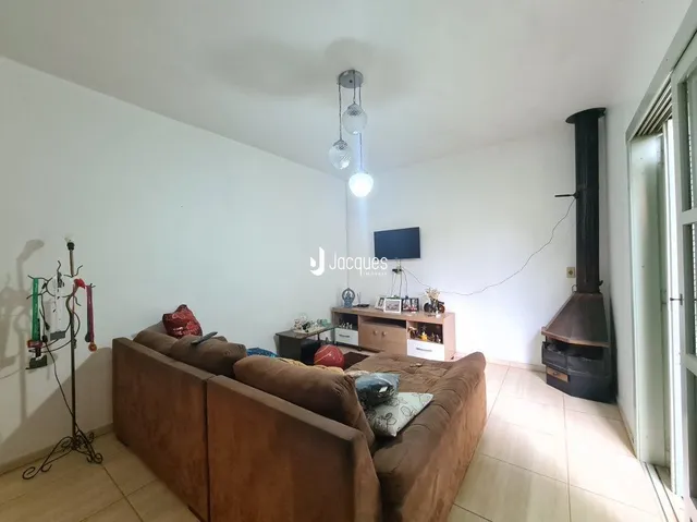 Sala de estar com sofá marrom e paredes brancas.