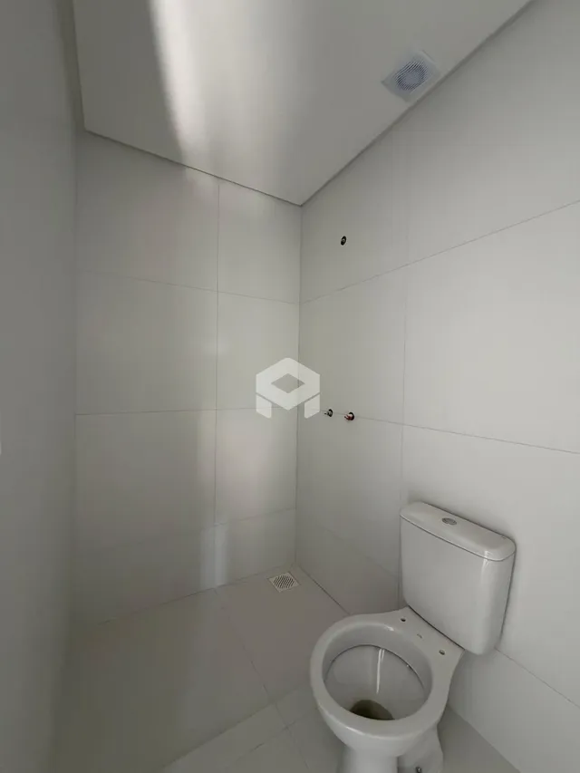 Foto de um banheiro com revestimento branco nas paredes e piso.