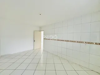 Corredor interno com piso de cerâmica branca e parede de azulejos.