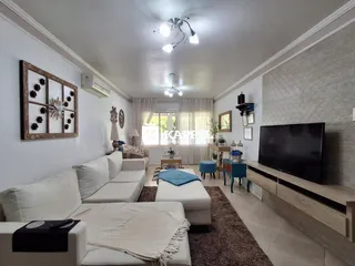 Sala de estar com sofá branco e televisão em ambiente claro.