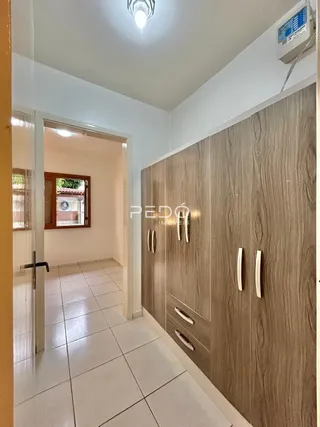 Hall de entrada com piso cerâmico e painel de madeira na parede.