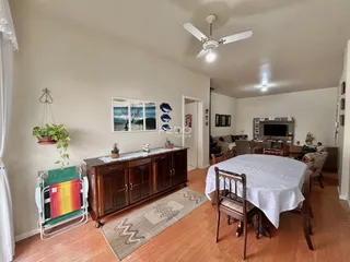 Ambiente interno de uma sala com mesa de jantar de madeira e piso de madeira.