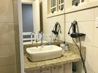 Foto de uma bancada de banheiro com pia e revestimento.