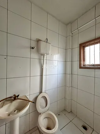 Foto de um banheiro com paredes de azulejo branco.