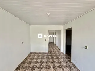 Um corredor interno com piso estampado e paredes brancas.
