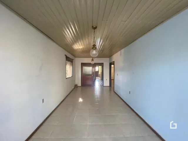 Corredor interno de uma residência com piso de cerâmica e paredes brancas.